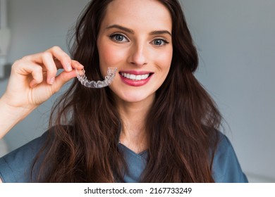 Young beautiful  woman holding dental aligner orthodontic to tee