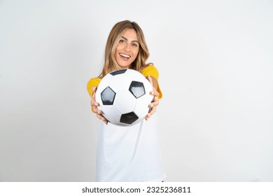 Young beautiful woman holding football ball over white background  cheerful and smiling poiting at camera