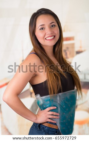 Young beautiful woman holding ice gel pack on her belly, medical concept, in office background