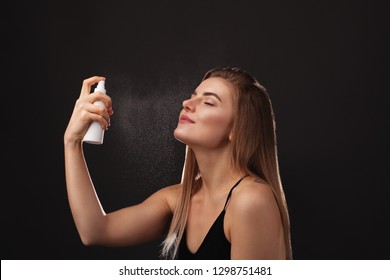 Young beautiful woman holding a jar of facial cream against dark background
