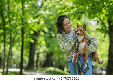 A young beautiful woman holds a dog in her arms for a walk. non-barking african basenji dog.  - Powered by Shutterstock