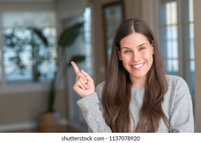 Young beautiful woman at home with a big smile on face, pointing with hand and finger to the side looking at the camera. - Shutterstock ID 1137078920
