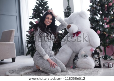 Young beautiful woman hug big teddy bear soft toy happy smiling at morning in bedroom. Funny girl and big toy bear.