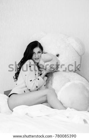 Young beautiful woman hug big teddy bear soft toy happy smiling at morning in bedroom. Funny girl and big toy bear. Valentine day gifts