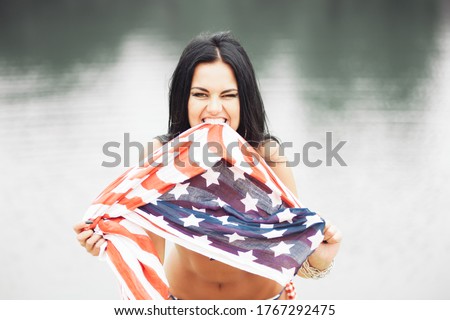 Young beautiful woman hugging an American flag on US Independence Day