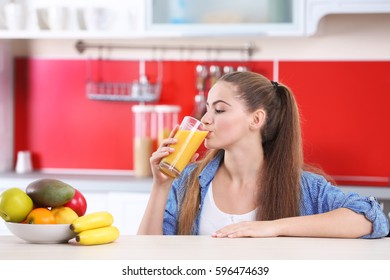 Young beautiful  woman  in kitchen drinking juice - Powered by Shutterstock