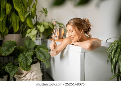 A young beautiful woman lies in a bath with foam and rose petals. Drinks champagne and white wine. The concept of pleasure, relaxation, spa and self-love. - Powered by Shutterstock