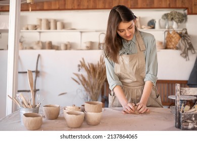 Young beautiful woman with long hair in an apron creates a handmade ceramic bowl from clay. Creative workshop. The concept of skill and entrepreneurship. copy space. - Powered by Shutterstock