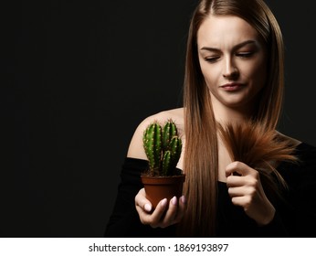 Young beautiful woman with long silky straight hair in black body comparing split ends with cactus in pot and feeling not satisfied over dark background. Haircare, beauty, wellness concept