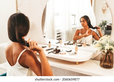 Junge schöne Frau mit langen dunklen Haaren und frisch sauberen Haut am Morgen machen die Routine vor der Arbeit, während sie vor dem Spiegel zu Hause sitzt. Schönheits- und Gesichtskosmetik-Konzept