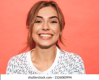 Young beautiful woman looking at camera. Trendy girl in casual summer shirt clothes with natural makeup. Positive female smiling. Funny model posing near pink wall in studio