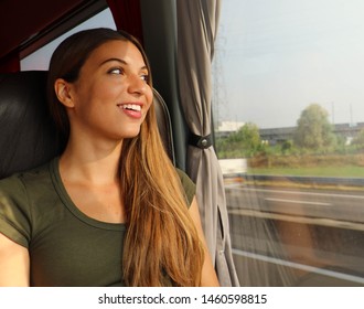 Young Beautiful Woman Looking Through The Bus Window. Happy Bus Passenger Traveling Sitting In A Seat And Looking Through The Window.