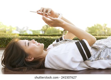 young beautiful woman lying on home terrace and playing smart phone in hand use for people and modern technology to connecting in social media and digital activities life style 