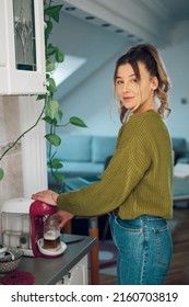 Young Beautiful Woman Making Fresh Espresso Coffee On The Machine In A Kitchen At Home. Barista Coffee Maker At Home. Coffee Machine Making Coffee.