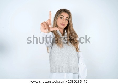 young beautiful woman making fun of people with fingers on forehead doing loser gesture mocking and insulting.