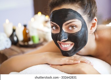 Young Beautiful Woman In A Mask For The Face Of The Therapeutic Black Mud. Spa Treatment