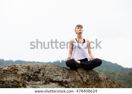 young beautiful woman meditating and doing yoga on top of the mountains