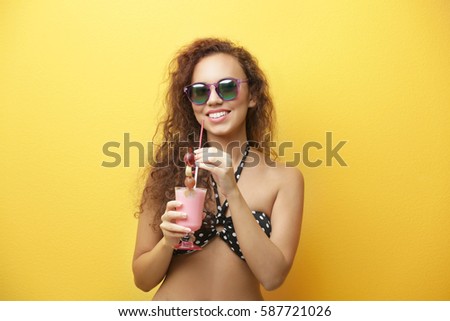 Young beautiful woman with milk shake on yellow background