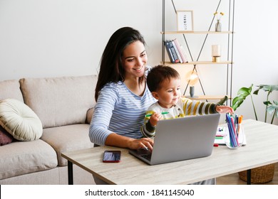 Young beautiful woman multitasking, working from home & teaching two year old son to draw. Woman spending quality time with her toddler child. Homeschooling concept. Close up, copy space, background. - Powered by Shutterstock