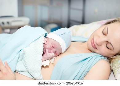 Young beautiful woman with a newborn baby after birth