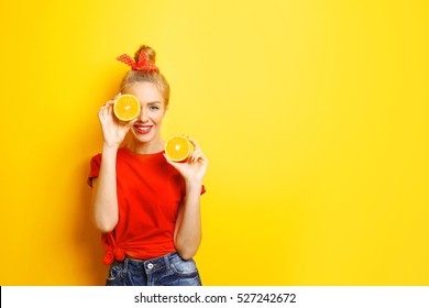 Young beautiful woman with orange on yellow background