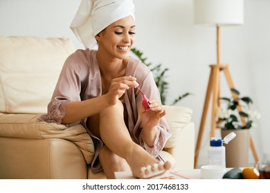 Young beautiful woman painting her toenails at home. 