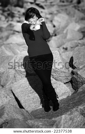 beautiful brunette short hair girl leaning against  gray rock wall outdoors, wearing black clothes