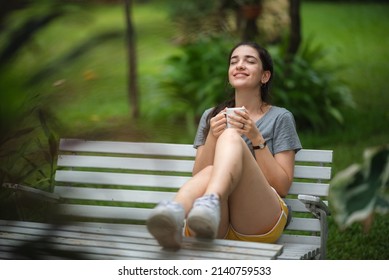 Young Beautiful Woman Person Are Happy And Enjoy With Coffee Drink In The Morning At Home, Relax Lifestyle By Holding Coffee Or Tea Cup At Nature Outdoor Park, Smile Pretty Girl With Freedom Time