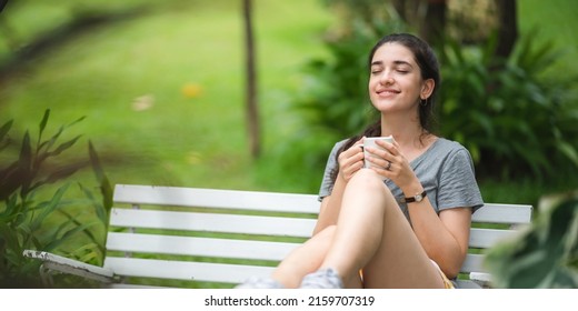 Young Beautiful Woman Person Are Happy And Enjoy With Coffee Drink In The Morning At Home, Relax Lifestyle By Holding Coffee Or Tea Cup At Nature Outdoor Park, Smile Pretty Girl With Freedom Time