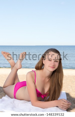young beautiful woman in pink bikini lying on the beach