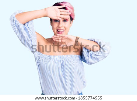 Young beautiful woman with pink hair wearing casual clothes smiling cheerful playing peek a boo with hands showing face. surprised and exited 