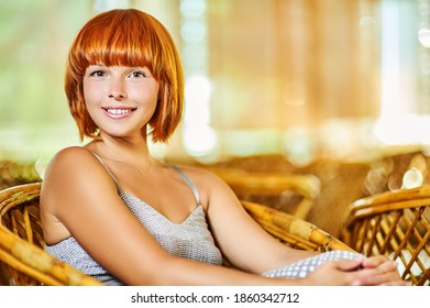Junge schöne Frau in einem gepolsterten Kleid, sitzend auf einem Holzwickler Stuhl und lächelt.