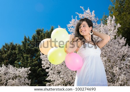 Young beautiful woman playing with colorful balloons, smiling and celebrating love and life in a spring scene.