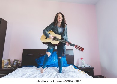 Young Beautiful Woman Playing Guitar Standing On Her Bed - Girl Power, Music, Having Fun Concept