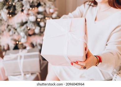 Young Beautiful Woman Plus Size Model In White Knitted Casual Sweater Sits In Living Room Near Christmas Tree And Opens Gift Boxes, Christmas And New Year Concept