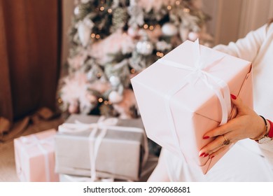 Young Beautiful Woman Plus Size Model In White Knitted Casual Sweater Sits In Living Room Near Christmas Tree And Opens Gift Boxes, Christmas And New Year Concept