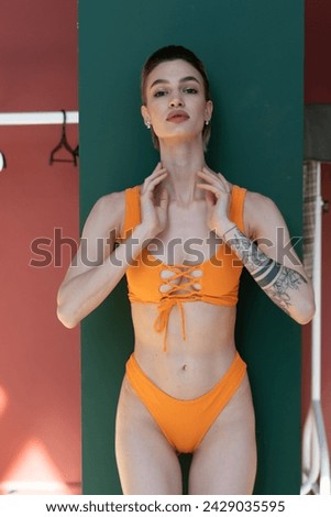 young beautiful woman posing in an orange swimsuit in the studio