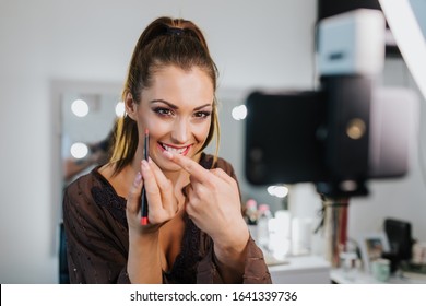 Young beautiful woman and professional beauty make up artist vlogger or blogger recording makeup tutorial to share on website or social media.
