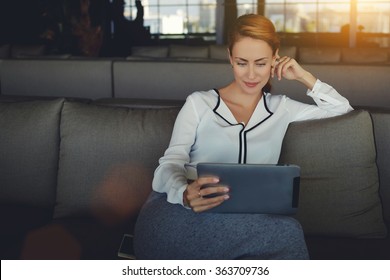 Young Beautiful Woman Reading Electronic Book Via Internet On Digital Tablet While Relaxing In Coffee Shop After Work Day, Modern Female Watching Fashion News On Touch Pad While Waiting Order In Cafe