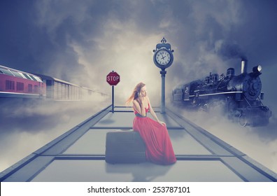 Young beautiful woman in red dress waiting old train on the platform of railway station. Dreamy foggy screen saver. Retro style vintage Instagram picture. Vacation voyage getaway adventure concept 