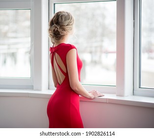 A young beautiful woman in a red evening dress. Beauty portrait of a model with a hairstyle