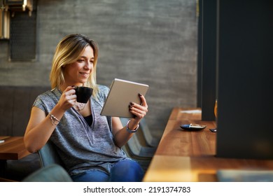 Young beautiful woman relaxing in coffee shop reading electronic book via internet on digital tablet and drink coffee - Powered by Shutterstock