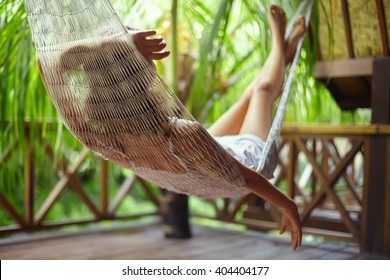 Young Beautiful Woman Relaxing In Hammock In A Tropical Resort.back View