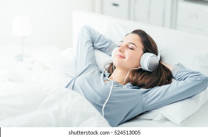 Young beautiful woman relaxing in her bed, she is listening to music and lying down with eyes closed - Powered by Shutterstock