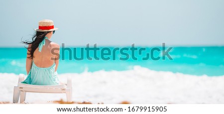 Young beautiful woman relaxing on the beach. Back view of happy girl on the seashore