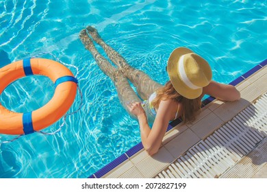 Young Beautiful Woman Is Relaxing And Swimming In The Blue Swimming-pool Closeup With Orange Lifesaver