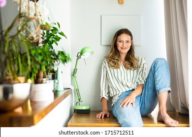 young beautiful woman resting and chilling next to a bright window, smiling and resting confortable