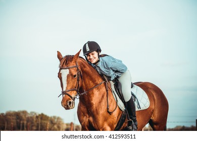 Young Beautiful Woman Rides A Horse Wearing A Helmet. Horseback Riding.