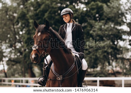 young beautiful woman rides a horse wearing a helmet. Horseback Riding.