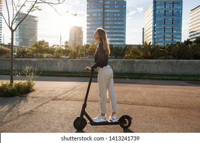 Young beautiful woman riding an electric scooter to work, modern girl, new generation, electric transport, ecology, ecological transport, sunset, electric skateboard, 4k - Powered by Shutterstock